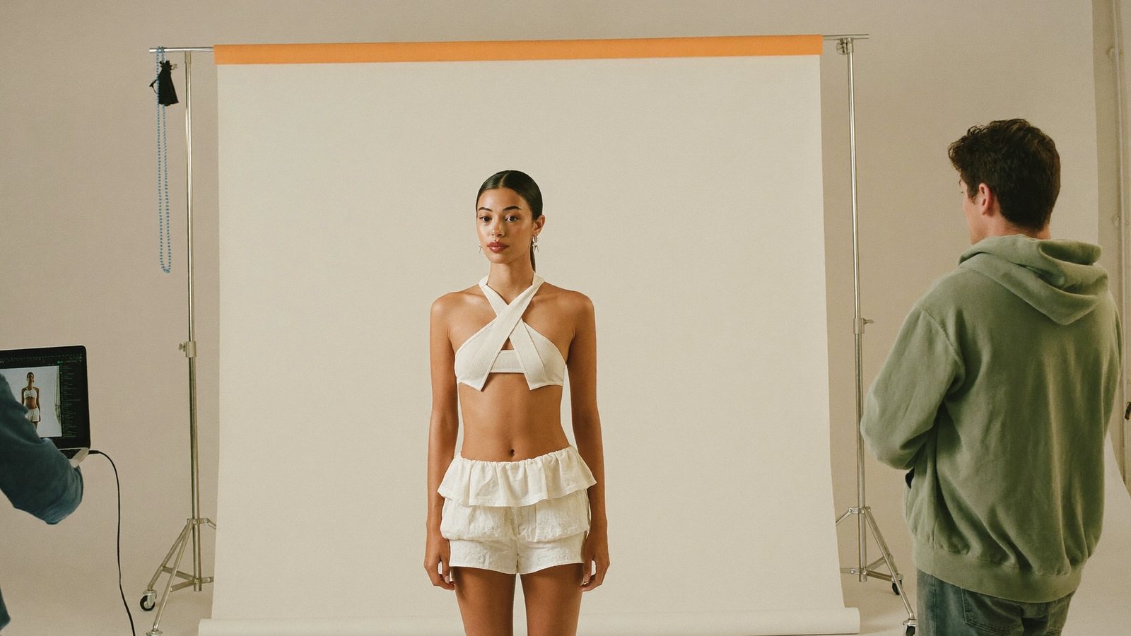 A working model on set in front of a seamless backdrop with crew