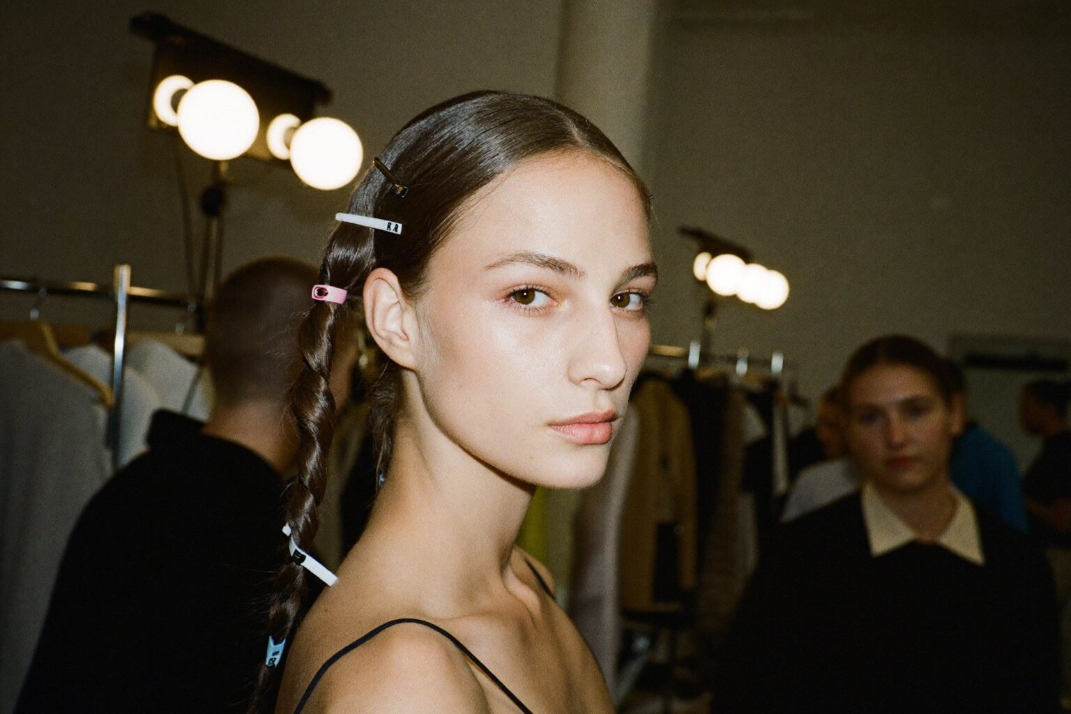 A model in runway hair and makeup looking back over her shoulder backstage before a show